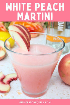 white peach martini in a glass garnished with sliced apples