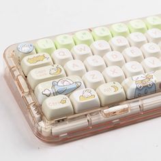 a clear plastic case holds a white and yellow keyboard with cartoon keys on it's sides