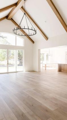 an empty living room with wood floors and large windows