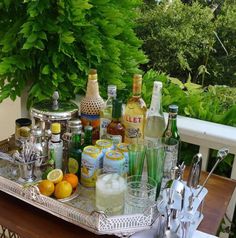 an image of a tray full of drinks and liquors on a table with trees in the background