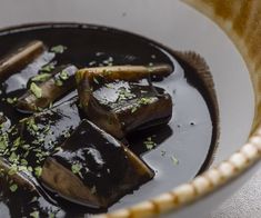 a white bowl filled with food and garnished in green stuff on top of a table