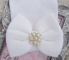 All our hospital hats are double ply, latex free, and made in USA, including the fabric. This white newborn hospital baby hat has a large bow attached made of the same fabric and is decorated with a silver rhinestone and pearl button attachment. There is NO personalization-- please agree to our ship date on checkout. It is designed to ensure your precious little girl stands out in the hospital nursery and you can announce her birth in style to your friends and all your social media uploads! Perf Hospital Nursery, Baby Hospital Hat, Newborn Hospital Hats, Lil Miss, Newborn Beanie, Newborn Hospital, Baby Hospital, Girl Standing, Baby Head