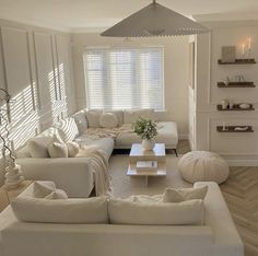 a living room filled with white furniture and decor on top of hard wood flooring