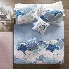 a bed with blue and pink comforters, pillows and blankets on top of it