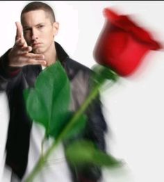 a man holding a red rose in his right hand and pointing at the camera with both hands