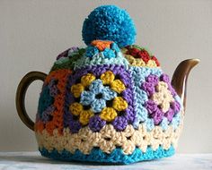 a crocheted tea pot with a wooden handle on top of a white table