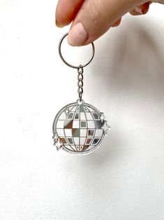 a hand holding a metal keychain with a globe on the front and bottom