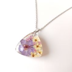 This pendant is made of real purple and white flowers and clear, non yellowing UV resistant resin. Stainless steel chain. 100% real photos - you will receive exactly the same pendant in a small box, well protected. Keep away from water, chemicals, cosmetics etc.. If you have some questions, don't hesitate to contact me. Best regards Desi White Heart-shaped Jewelry With Pressed Flowers, White Heart Jewelry With Pressed Flowers, Clear Flower Pendant Necklace As Gift, Clear Flower Pendant Necklace For Gift, Floral Print Flower Necklaces For Gifts, Clear Flower-shaped Necklace For Gift, Handmade Clear Flower Necklace, Clear Flower Necklace For Gift, Purple Flower Necklace For Gift