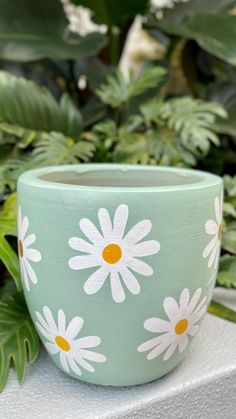 a green pot with white daisies painted on it