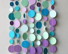 a multicolored paper mobile hanging from a wall with circles and dots on it