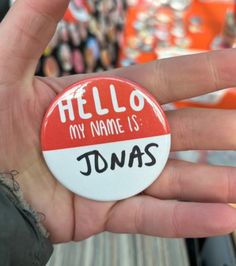 a hand holding a button that says, hello my name is tomass on it