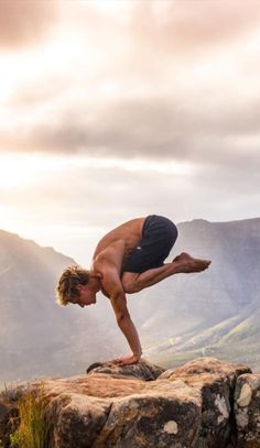 a man doing a handstand on top of a rock