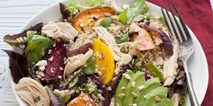 a salad with chicken, lettuce, tomatoes and other vegetables on a white plate