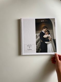 a person holding up a wedding photo book