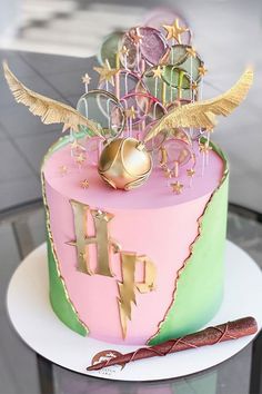 a pink and green cake sitting on top of a glass table next to a pen