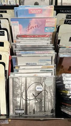 many cds are stacked on top of each other in a store display case with the word love written on them