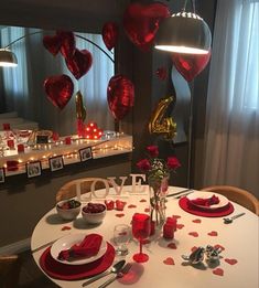 the table is set for valentine's day with hearts hanging from the ceiling