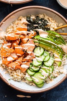 salmon, rice and cucumber stir fry in a bowl with chopsticks