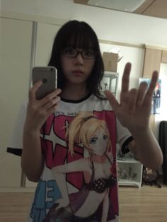 a girl with glasses is holding up her cell phone in front of her face and making the peace sign