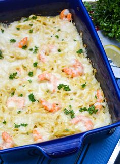 a casserole dish with shrimp and noodles in a blue pan on a table