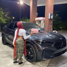 a woman standing next to a gray car