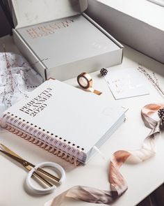 an open notebook sitting on top of a table next to some scissors and other items