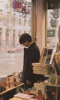 a man standing in front of a book stand filled with books