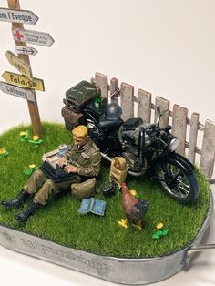 a figurine is sitting in the grass next to a motorcycle and some signs