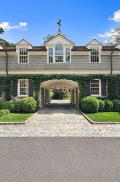 the front entrance to a large house with hedges and bushes on either side of it