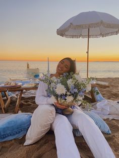 a woman is sitting on the beach with flowers