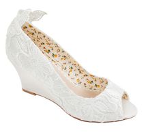 a pair of white wedges with flowers on the top and lace detailing, in front of