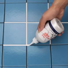 a person is using a toothbrush to brush their teeth on blue tile flooring