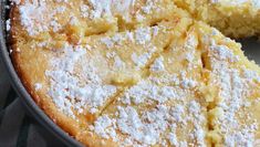 a close up of a cake with powdered sugar on it and one slice missing