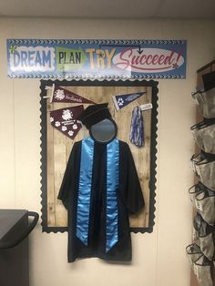 a graduation cap and gown hanging on a wall in front of a sign that says dream plan try success