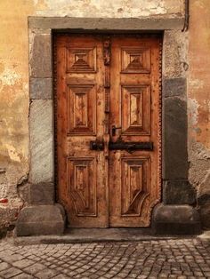 an old wooden door is open on the side of a building with cobblestone flooring