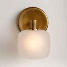 a bathroom light that has a white glass shade on the top and gold trim around it