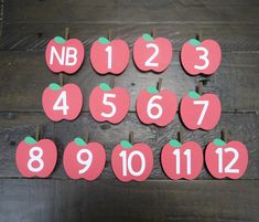 the numbers and apples are arranged in rows on wooden boards with pegs attached to them