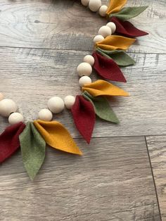 a necklace made out of felt and wood beads on a wooden table with other items