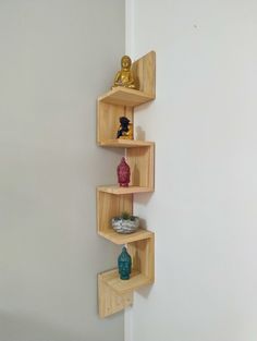 three wooden shelves on the wall with vases and statues sitting on top of them