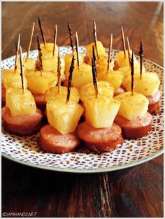 some food is sitting on a plate with toothpicks in the shape of pineapples