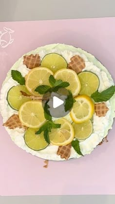 a cake decorated with lemons, mint and ice cream on a pink tablecloth