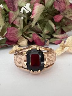 A stunning statement ring that demands attention!  Crafted in luxurious 9ct yellow gold, this signet ring holds a rich, deep dark red rectangular Garnet that instantly draws the eye. It is complemented by intricately embellished shoulders that add  a touch of opulence and sophistication. The tapered shank ensures a comfortable fit, making this ring perfect for those who love to stand out in style.  Whether you're dressing up for a special occasion or simply want to add a little drama to your eve Dress Ring, Statement Dress, Dress Rings, Red And Gold, Ring Box, Signet Ring, Statement Ring, Sterling Silber, Dark Red