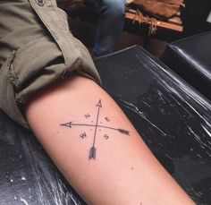 a person with a tattoo on their arm that has an arrow and two arrows in it