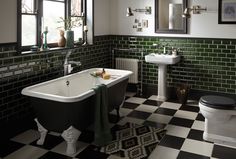 a black and white checkered floor bathroom with green tiles on the walls, an old fashioned bathtub in the middle