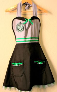 a black and white dress with green trims hanging on a wall next to a wooden hanger