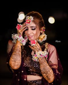 a woman wearing henna and holding her hands to her face with flowers on it