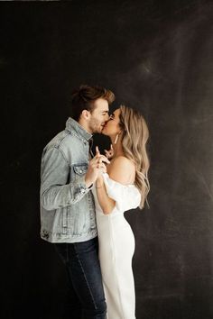 a man and woman kissing each other in front of a chalkboard wall with black background