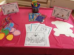 a pink table topped with lots of cards and paper cut outs on top of it