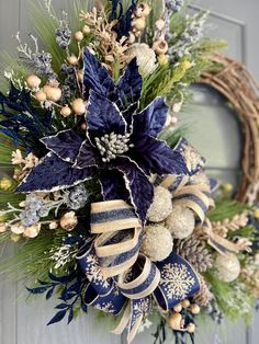 a wreath with blue and gold decorations hanging on the front door for holiday decorating