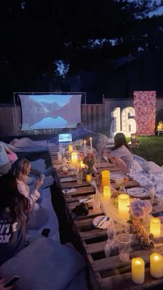 people sitting at a table with candles on it in the middle of a movie screen